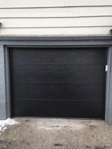 A home with cream colored siding and a black garage door with no windows.