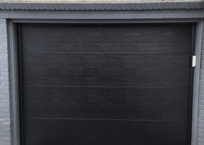 A home with cream colored siding and a black garage door with no windows.